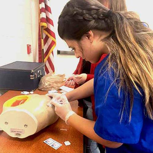 Jenny Duran is doing a venipuncture to obtain blood for testing.